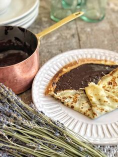 two slices of chocolate dessert on a plate with lavenders and a copper pot in the background