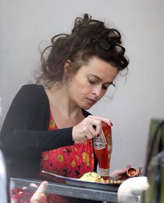 a woman sitting at a table with a plate of food and a bottle of ketchup