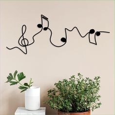 music notes are hanging on the wall above a potted plant and a white vase