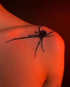 a black spider tattoo on the back of a woman's upper arm and shoulder