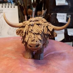 a sculpture of a bull's head on top of a pink surface with pens and pencils in the background