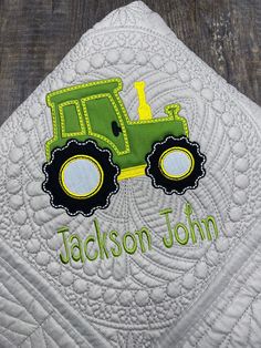 a quilted pillow with a tractor on it and the name jackson john written in green