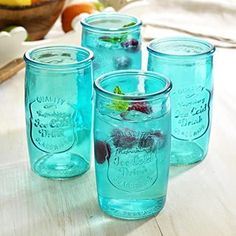 four blue mason jars sitting on top of a wooden table