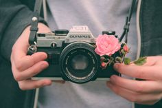 a person holding a camera with a flower on it