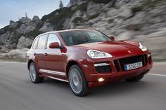 a red porsche cayen driving down the road