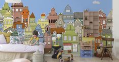 a child is sitting on a bed in front of a colorful city wall paper mural