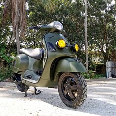 a green scooter parked in front of some trees