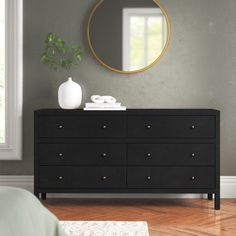 a bedroom with a dresser, mirror and plant on the side table in front of it