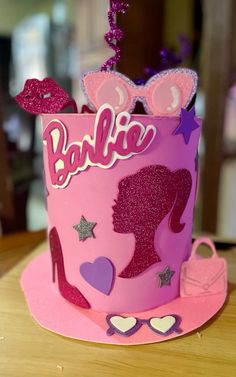 a pink birthday cake with glitter decorations on it's top and the word barbie written in large letters