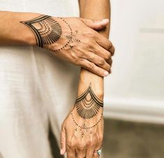 two hands holding each other with tattoos on their arm and wrist, both showing the same design