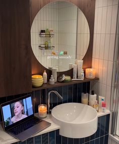 a laptop computer sitting on top of a bathroom counter next to a sink and mirror