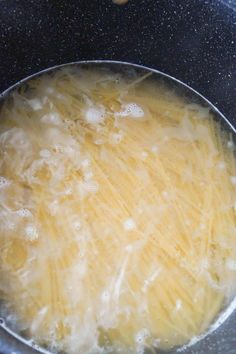 pasta is being cooked in a pan on the stove top, with oil and water