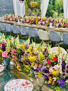 a table set up with plates and flowers on it for an outdoor wedding or party