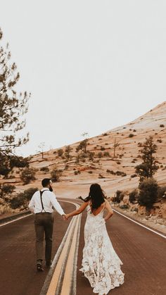 a bride and groom walking down the road holding hands