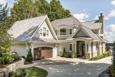 a large white house with two garages on the front and one story, surrounded by trees