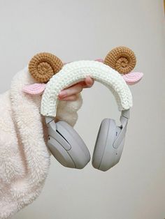 a person wearing headphones holding up a stuffed animal with ear muffs on it's ears