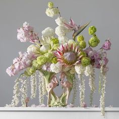 a vase filled with flowers and two pink flamingos