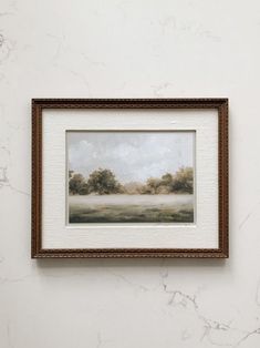 a painting hanging on the wall above a white counter top next to a framed object