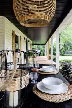 an outdoor dining area with wicker baskets and white plates on the black wood table