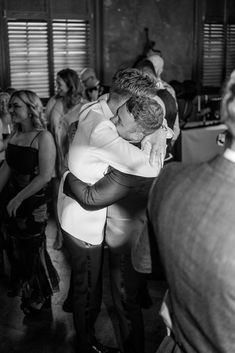 black and white photograph of two men hugging each other in the middle of a crowd