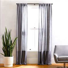 a living room with a chair, potted plant and window