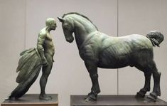 a statue of a man and a horse next to each other on pedestals in a room