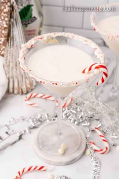 two martinis with candy canes in them on a white countertop next to christmas decorations