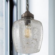 a glass light fixture hanging from a ceiling in a room with white walls and windows