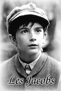 black and white photograph of a young boy wearing a sweater vest, tie and hat