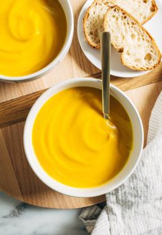 two bowls of soup with bread on the side