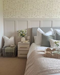 a bedroom with a bed, nightstand and flowers on the side table in front of it