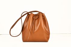 The high-quality Classic Bucket Bag is a practical companion for every occasion. The bag is made of supple, vegetable-tanned cowhide with a great stand. The handle is adjustable and therefore the bag can be worn flexibly either over the shoulder or crossbody. This bag will accompany you throughout your life! Bag dimensions: Height: 29 cm Width: 25 cm Depth: 17 cm Handle length: min.: 80 cm max.: 120 cm Leather is a natural product, each bag has a different pattern! The Classic Bucket Bag is prod Luxury Calf Leather Bucket Bag In Cognac, Tan Cowhide, Cognac, Real Leather, Purses And Handbags, Bucket Bag, Shoulder Bags, Genuine Leather, Bathing Beauties