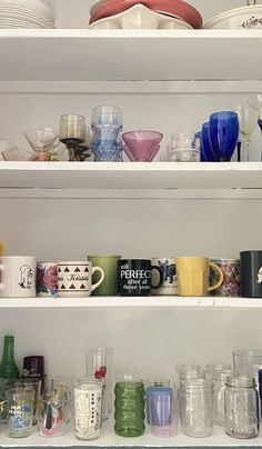 the shelves are filled with dishes and cups on it's sides, including one that is full of glasses