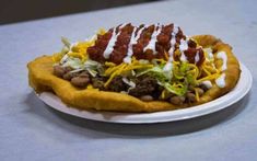 a white plate topped with a taco covered in sauce and toppings on top of it