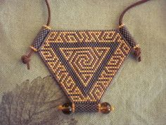 the beaded triangle is hanging on a brown leather cord and has beads attached to it