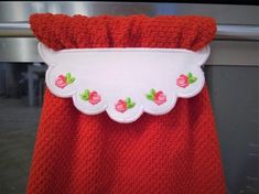 a red blanket with white trim and pink roses on the bottom is hanging in front of a metal door