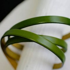 two green leather bracelets sitting on top of a white cloth