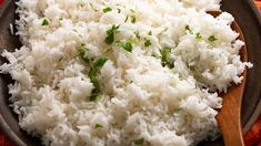 white rice in a bowl with a wooden spoon on the side and an orange towel behind it