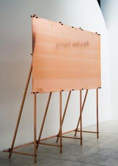 a large wooden sign sitting on top of a cement floor next to a white wall