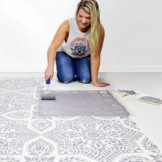 a woman kneeling down on the floor painting