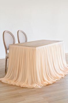 an empty table with two chairs and a cloth draped over it on a hard wood floor