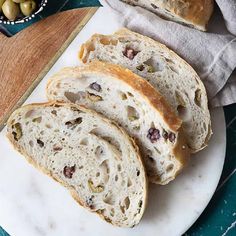 slices of bread sitting on top of a white plate next to an olives bowl