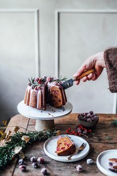 a person is cutting into a cake on a wooden table with other plates and food