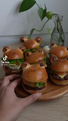 small hamburgers with googly eyes are on a wooden tray