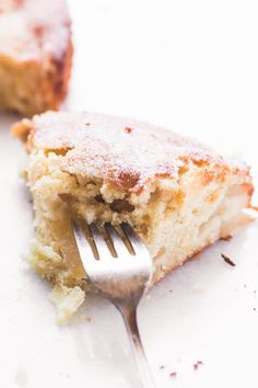 a close up of a fork on a piece of cake with powdered sugar and icing