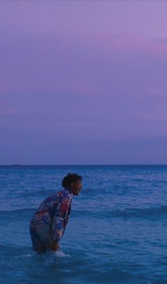 a man standing in the ocean with a frisbee