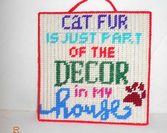 a cross stitch sign that says, cat fur is just part of the decor in my home