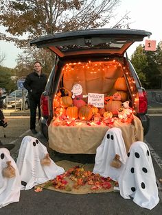 the back of a van decorated for halloween with ghost decorations and pumpkins in the trunk