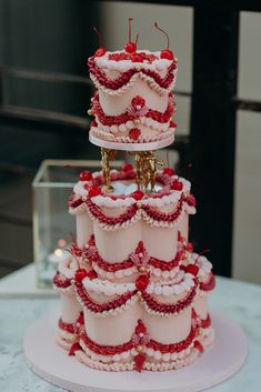 a three tiered cake with red and white decorations on the top is sitting on a table