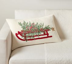 a white couch with a christmas pillow on it's back and an embroidered santa sleigh